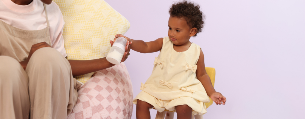 toddler holding glass bottle