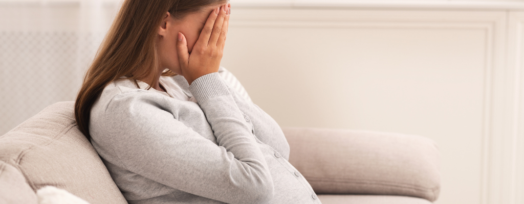 pregnant woman crying on couch